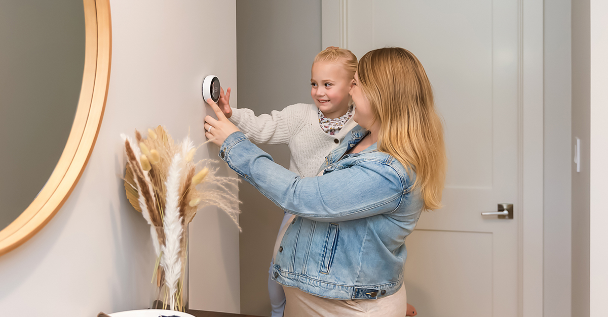 A mom and daughter setting a smart thermostat